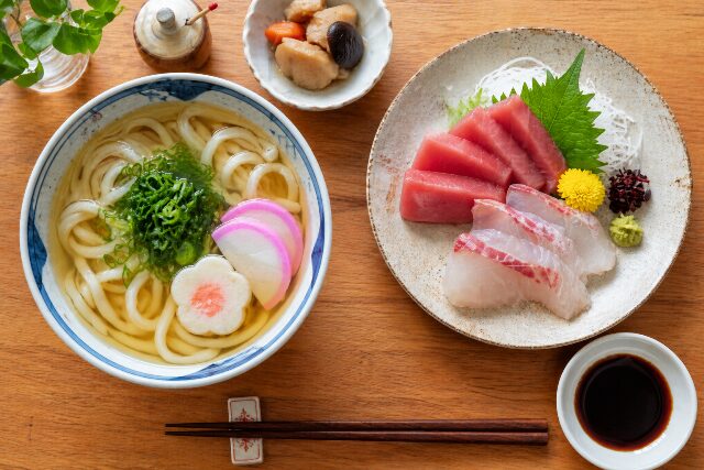 薄口醤油で澄んだスープに仕上げたうどんと、濃口醤油で食べるお刺身の使い分けイメージ。
